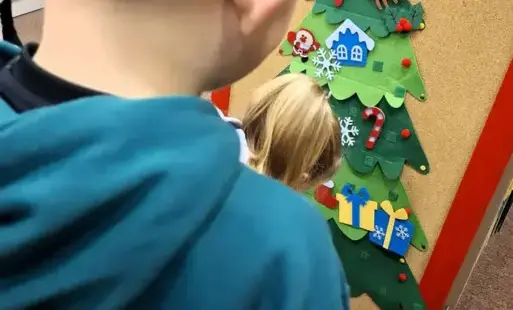 Dzieci dekorują filcową choinkę. 