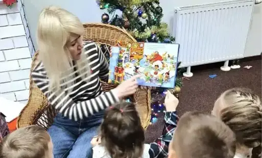 Bibliotekarka czyta dzieciom zimową książkę. 