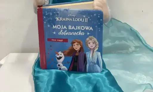  Zdjęcie startowe: siedząca lalka Elsa z książką „ Kraina lodu”