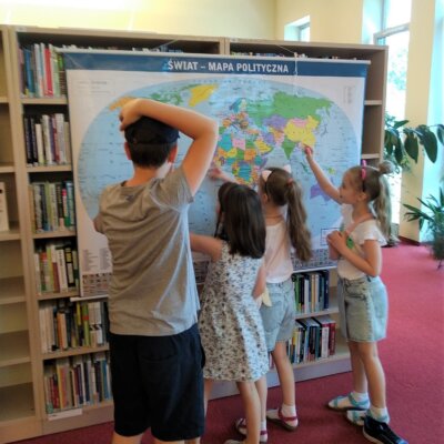 Czworo dzieci stoi przy mapie, pokazują wybrane państwa.
