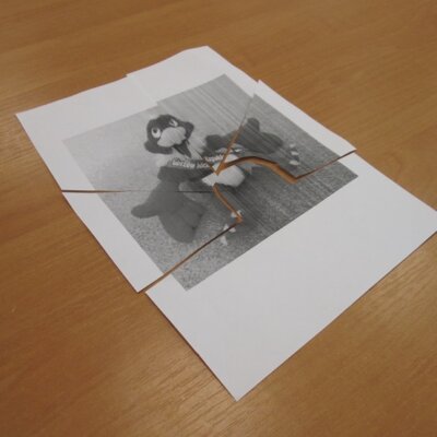 Puzzle z pociętej kartki A4 z wizerunkiem maskotki Gorzowa Wielkopolskiego, Gorzusiem leżące na stole.. Klikniecie powoduje powiększenie zdjęcia