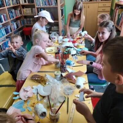 Dzieci przy stoliku wykonują krasnoludki z papierowych talerzy oraz koziołki z rolek