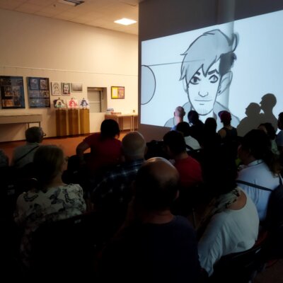 Goście oglądają wyświetlaną na ścianie kolejną prezentację z animacjami komputerowymi – dziełem autora prac. Kliknięcie powoduje powiększenie zdjęcia.