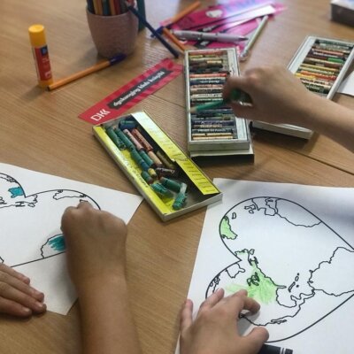 Dzieci wykonują samodzielnie pracę plastyczną przedstawiającą kontur mapy świta. Kliknięcie powoduje powiększenie zdjęcia.
