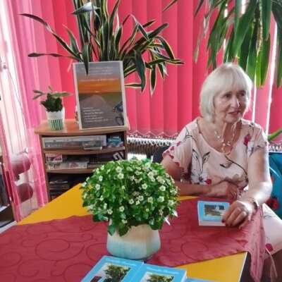 Autorka tomiku poezji przy stole z kilkoma egzemplarzami swojej książki