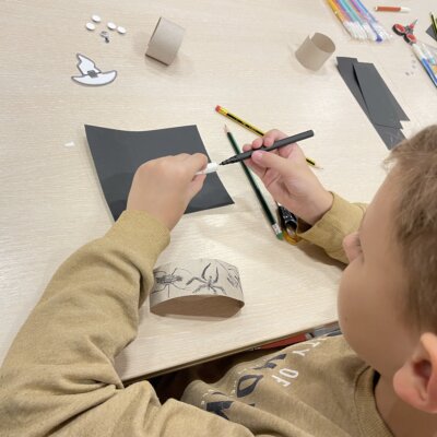 Dziecko odrysowuje element dekoracyjny na bransoletkę. Kliknięcie powoduje powiększenie zdjęcia.