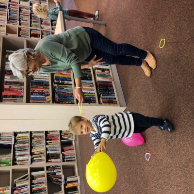 Dziecko przesuwa balonem po sznurku trzymanym przez babcię. Kliknięcie powoduje powiększenie zdjęcia.