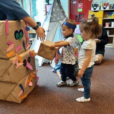 Dzieci z Panią Bibliotekarką ustawiają udekorowane kartony, tworząc biblioteczny totem.