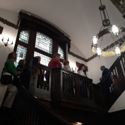 Zdjęcie na schodach Willi Lehmanna. Widać stojących bokiem uczestników spotkania i przewodnika. kliknięcie powoduje powiększenie zdjęcia.