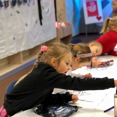 Dzieci siedzą przy stole i za pomocą mazaków malują aluminiową folię. Kliknięcie w obrazek spowoduje powiększenie.