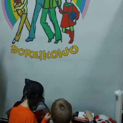 Dwóch chłopców wykonuje rysunek. Na ścianie napis Borejkowo. Kliknięcie powoduje powiększenie zdjęcia.