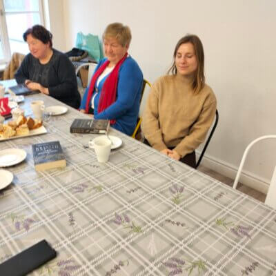 Trzy uśmiechnięte panie siedzą przy stole, na którym leży omawiana książka. Kliknięcie powoduje powiększenie zdjęcia.