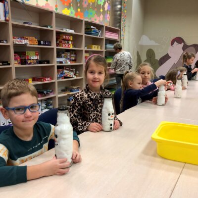 Dzieci na pierwszym planie prezentują bałwanki, czyli szklane butelki wypełnione watą. Kliknięcie powoduje powiększenie zdjęcia.