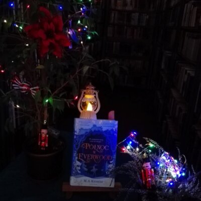 Książka „Północ w Everwood” M.A. Kuzniar na małej sztaludze, obok lampki. Kliknięcie w obrazek spowoduje powiększenie.