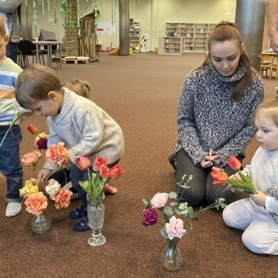 Maluchy wkładają zebrane bukiety kwiaty do wazonów.