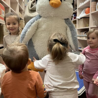 Maluchy trzymają dużego pluszowego pingwina. Kliknięcie powoduje powiększenie zdjęcia.
