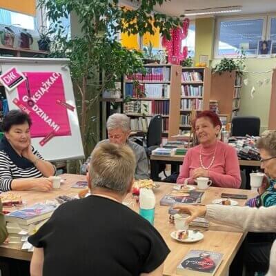 Wszystkie uczestniczki spotkania DKK siedzą przy stole i dyskutują o treści książki. Kliknięcie w obrazek spowoduje powiększenie.
