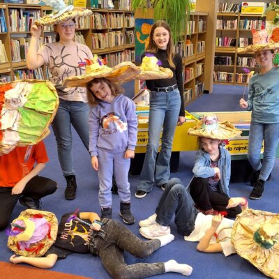 Dzieci pozują w zrobionych przez siebie kapeluszach. Kliknięcie powoduje powiększenie zdjęcia.