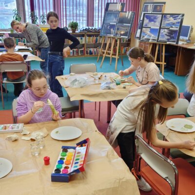 Dzieci przy stołach malują wcześniej wykonane figurki z gliny. Kliknięcie powoduje powiększenie zdjęcia.