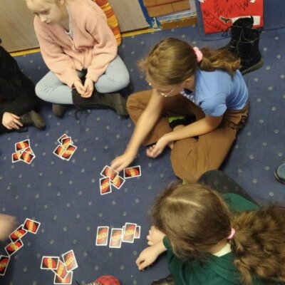 Grupa dzieci w kole gra w karty. Kliknięcie powoduje powiększenie zdjęcia.