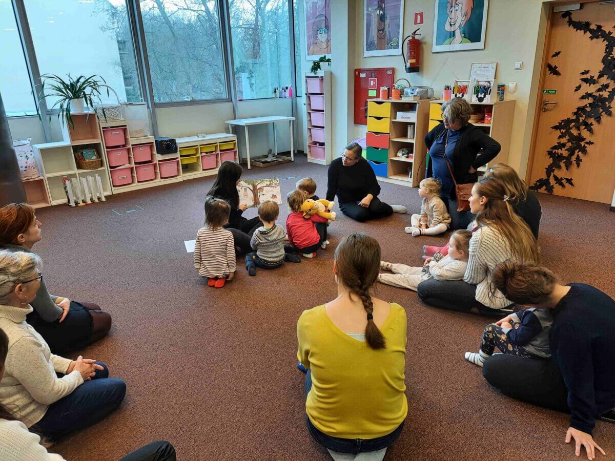 Dzieci w skupieniu słuchają książki czytanej przez panią Bibliotekarkę.