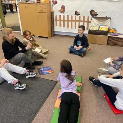 Dzieci wraz z prowadzącą, która trzyma pacynkę lisa siedzą na dywanie i rozmawiają na temat przeczytanej książki. Kliknięcie powoduje powiększenie zdjęcia.