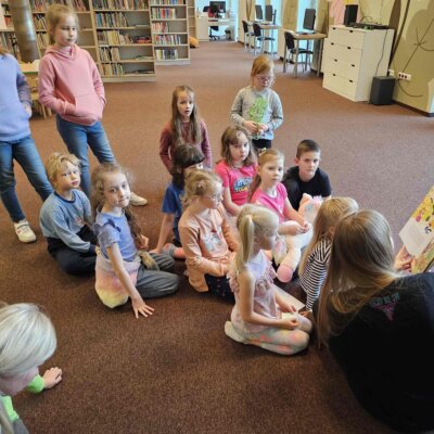 Dzieci słuchają książki czytanej przez Panią Bibliotekarkę. Kliknięcie w obrazek spowoduje powiększenie.