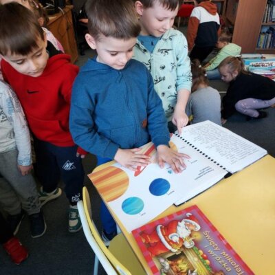 Przedszkolaki stojące przy stoliku oglądają książki. Kliknięcie w obrazek spowoduje powiększenie.