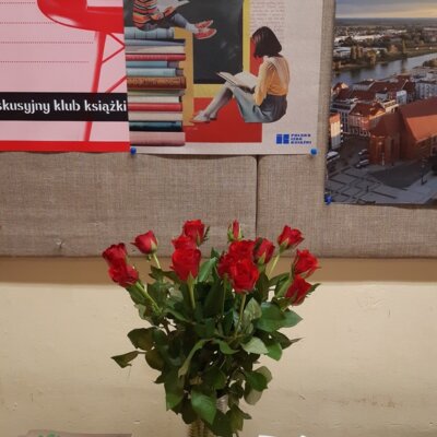 Wnętrze Filii nr 8. Widok na biurko. Na środku wazon z czerwonymi różami, rozłożone zakładki do książek. W tle plakat promujący Światowy Dzień Książki i Praw Autorskich. Kliknięcie w obrazek spowoduje powiększenie.