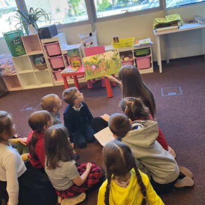 Dzieci w skupieniu słuchają książki czytanej przez Panią Bibliotekarkę. Kliknięcie w obrazek spowoduje powiększenie.