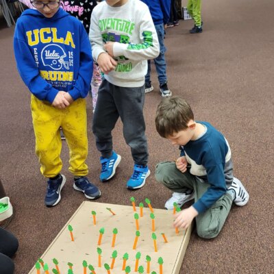 Przedszkolaki umieszczają marchewki w wyciętych miejscach na kartonie. Kliknięcie w obrazek spowoduje powiększenie.