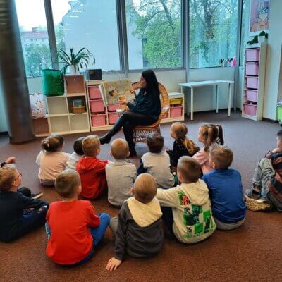 Dzieci w skupieniu słuchają książki czytanej przez Panią Bibliotekarkę. Kliknięcie powoduje powiększenie zdjęcia.