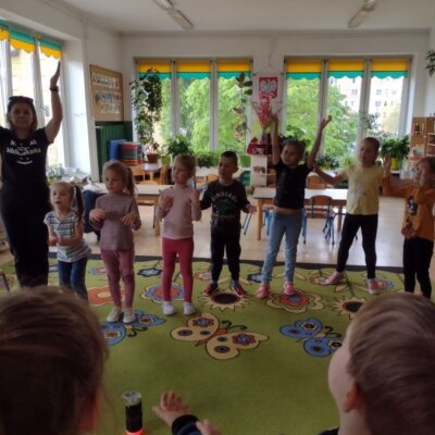 Dzieci stoją w okręgu i wykonują gesty do piosenki. Kliknięcie powoduje powiększenie zdjęcia.