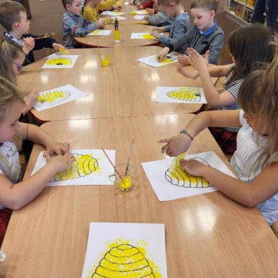 Dzieci za pomocą folii bąbelkowej odbijają żółtą farbę na wydrukowanych ulach. Kliknięcie w obrazek spowoduje powiększenie.