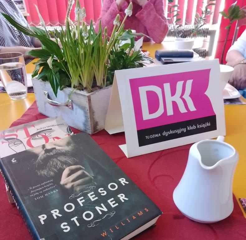 na stole ksiązki, napis DKK, kwiaty i filiżanki