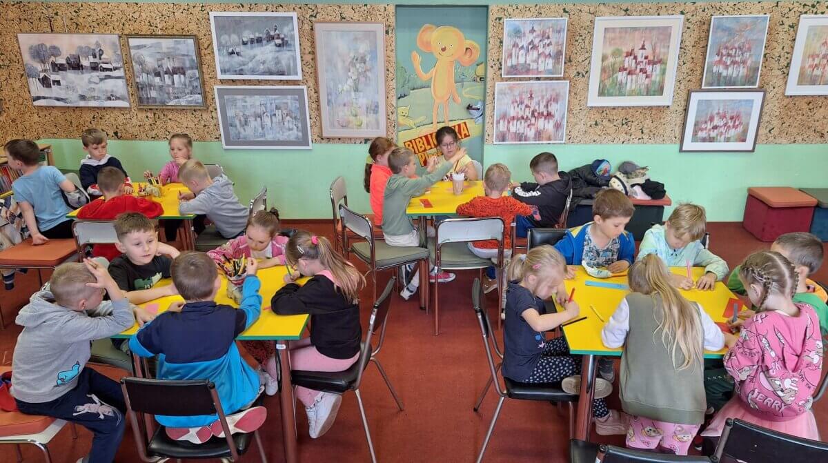 Przy czterech stolikach dzieci wykonują kolorowe zakładki do książek.